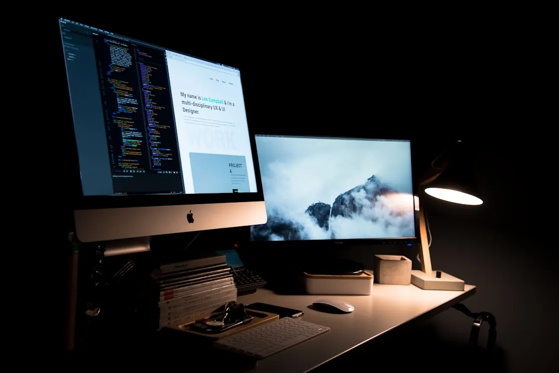 An editor and the page it produces, side by side on a desk at night.